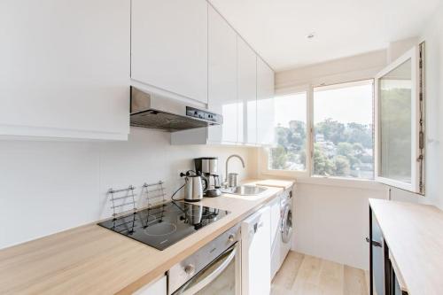 a white kitchen with a sink and a counter at Private room in renovated apartment - Tram 1 min walk in Nice