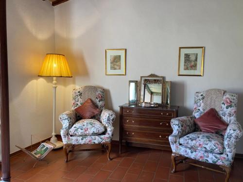 a room with two chairs and a lamp and a dresser at Podere La Paolina in Montefollonico