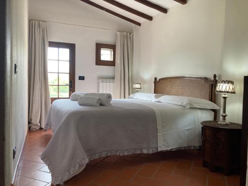 a bedroom with a bed with white sheets and a window at Podere La Paolina in Montefollonico