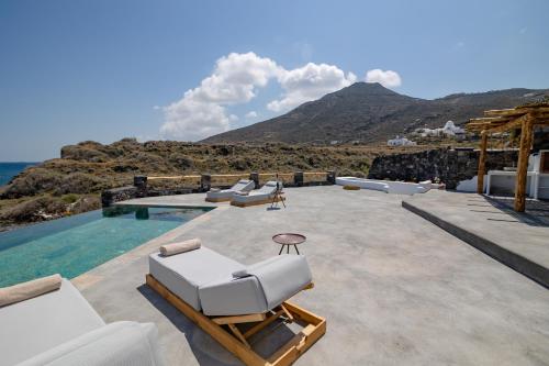 a pool with white chairs and a view of the ocean at Casa di Mare Luxury Villas in Imerovigli