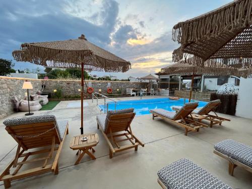 a patio with chairs and umbrellas and a swimming pool at Koukounari Apartments in Skala