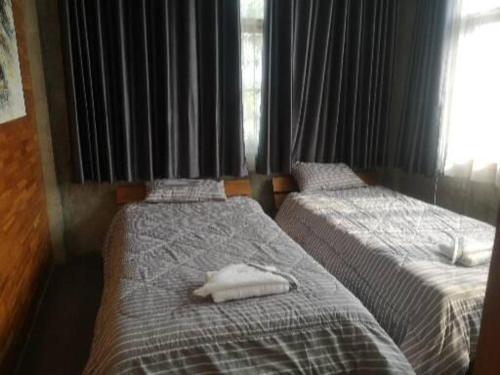 - une chambre avec 2 lits avec des draps blancs et une fenêtre dans l'établissement ป้าเฒ่าเฝ้าสวน, à Lampang