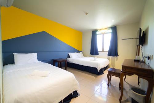 a bedroom with two beds and a desk and a window at The Colony by Cactus Hotel Dedap in Johor Bahru