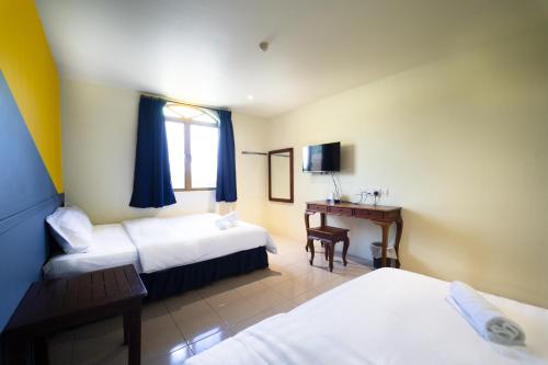 a hotel room with two beds and a desk at The Colony by Cactus Hotel Dedap in Johor Bahru