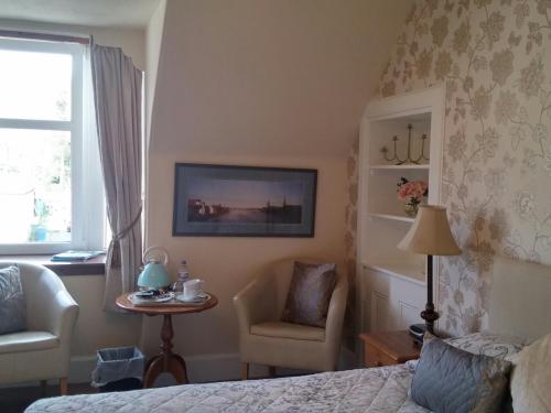 a bedroom with a bed and a chair and a tv at Heathcote B&B in Inverness