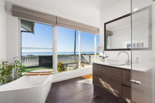 a bathroom with a bath tub and a large window at THE DECK HOUSE - Beautiful Busselton Beachfront in Busselton