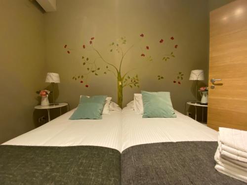 um quarto com uma cama com uma árvore na parede em Refitolería Apartamentos na Segóvia