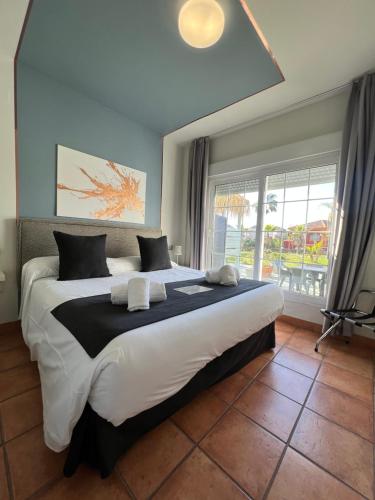 a large bed in a bedroom with a large window at ON Family Playa de Doñana in Matalascañas