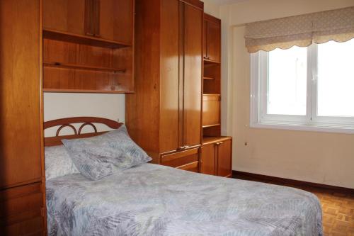Schlafzimmer mit einem Bett, Holzschränken und einem Fenster in der Unterkunft Vibes Coruña-Finisterre 288 in A Coruña