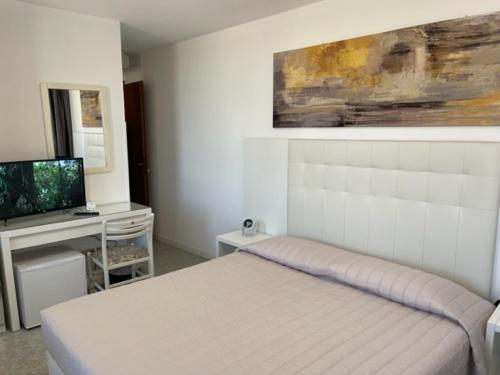 une chambre blanche avec un lit et une télévision dans l'établissement Euro Meublé, à Grado