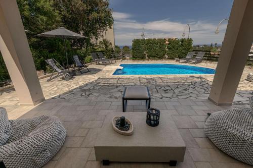 a patio with a pool with chairs and a table at Villa Emma in Gerani