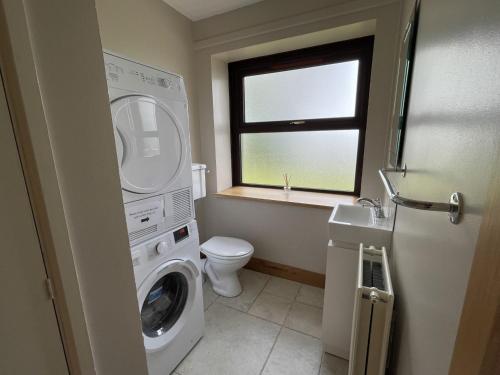 a bathroom with a washing machine and a toilet at Bar View House in Newry