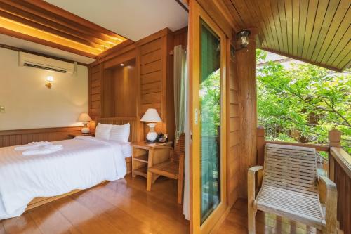 a bedroom with a bed and a large window at Vanasin Residence in Tak