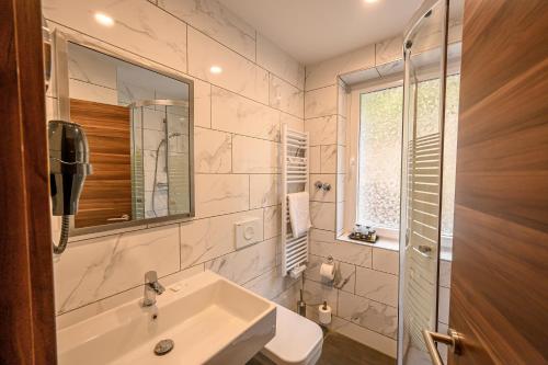 Baño blanco con lavabo y espejo en Hotel Schwarzbachtal Hideaway en Erlbach