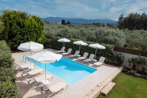 a swimming pool with umbrellas and chairs and a pool at Villa Lucas in Melidhónion