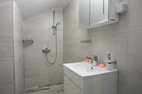 uma casa de banho branca com um lavatório e um chuveiro em Къща за гости КООП Флорал / COOP Floral Guest House 
