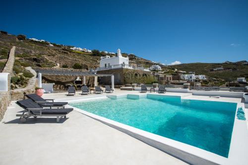 un uomo seduto su una sedia accanto alla piscina di Villa Jet by Mykonos Rocks a Mykonos Città