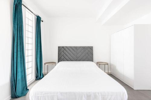 - une chambre avec un grand lit blanc et des rideaux bleus dans l'établissement Agréable appartement prés de Paris - II, aux Lilas