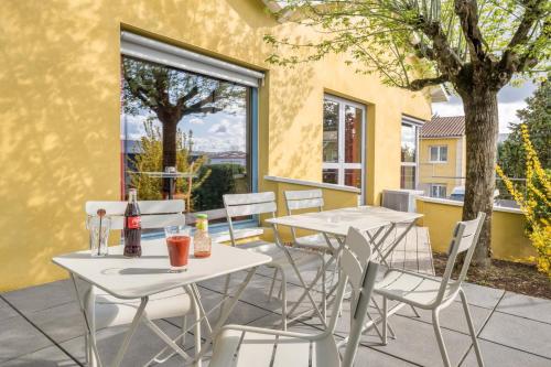 - deux tables et des chaises avec des boissons sur la terrasse dans l'établissement Hôtel Newport, à Villefranche-sur-Saône
