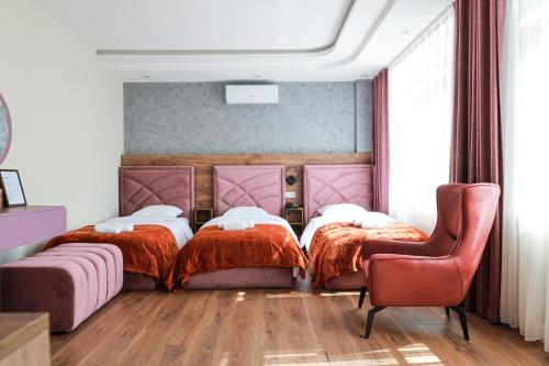 two beds in a room with a chair and a couch at Nafron Hotel in Prizren