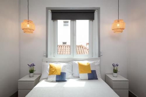 Un dormitorio con una cama blanca con almohadas amarillas y azules en Minimalist Apartment In Caldas, en Caldas da Rainha