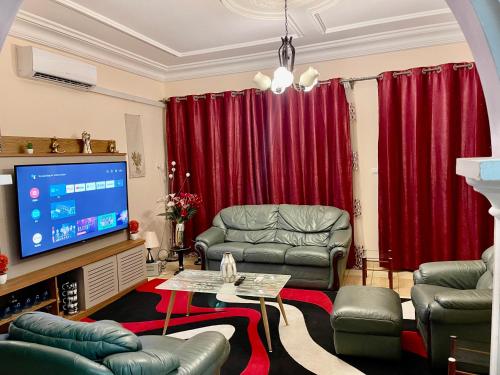 sala de estar con cortinas rojas y TV de pantalla plana en The Palace, en Douala