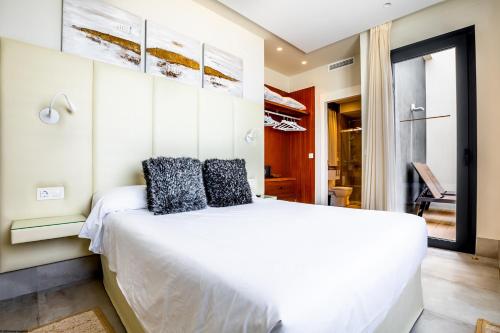 a bedroom with a large white bed with black pillows at ON Village in Matalascañas