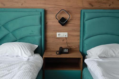 a bedroom with two beds and a phone on a night stand at Nafron Hotel in Prizren