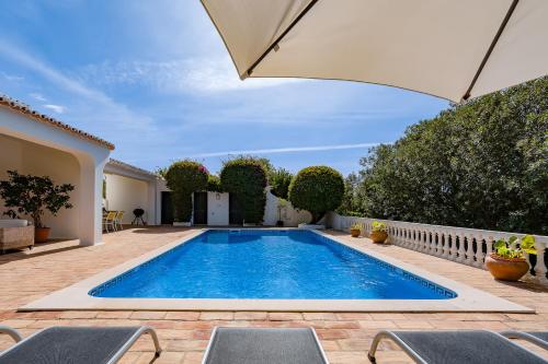 una piscina en un patio trasero con sombrilla en Casa Luzerna, en Carvoeiro