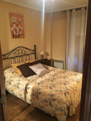a bedroom with a bed with a floral bedspread at Apartamento en el centro de asturias in Langreo