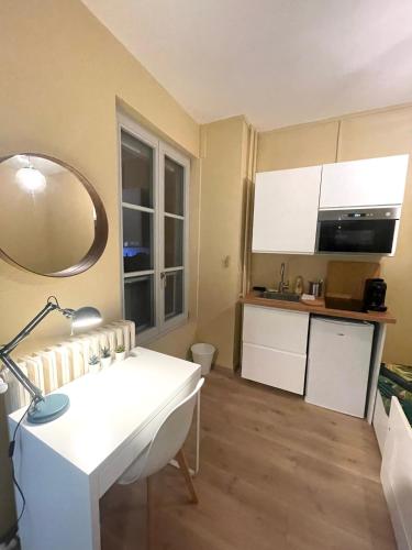 um pequeno quarto com uma mesa branca e uma cozinha em Petit Studio Centre-Ville n°6 em Besançon