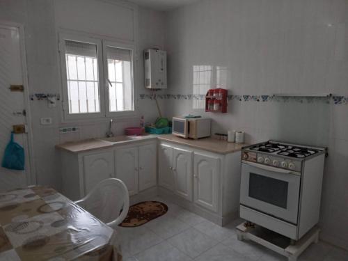 cocina blanca con fogones y microondas en Confortable Maisonnette prés de la plage à Dar el Alouch, en Kelibia