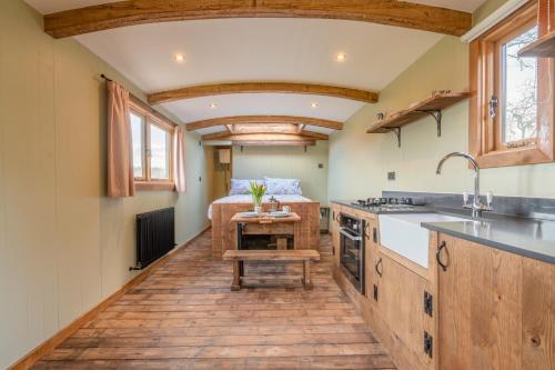 a kitchen with wooden flooring and a kitchen with a table at Bertha Shepherd's Hut in Lydney