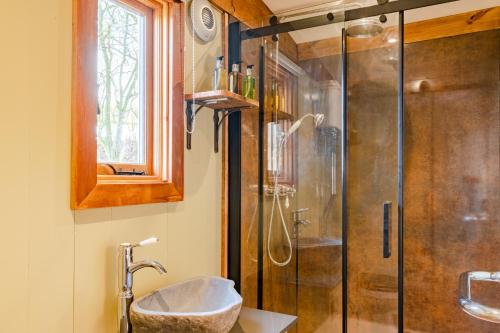 a bathroom with a shower and a sink at Bertha Shepherd's Hut in Lydney