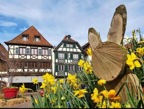 L'Appar'T - Centre historique de Obernai في أوبرناي: منزل به تمثال فراشة أمام الزهور