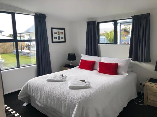 a bedroom with a white bed with red pillows at Amberlea Cottages in Hokitika