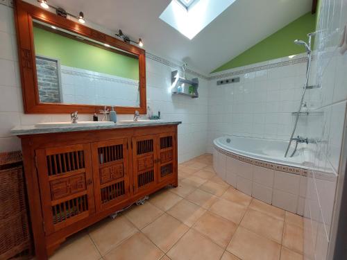 une salle de bain avec une baignoire, un lavabo et un miroir dans l'établissement Gite Le Piboul, à Espinas