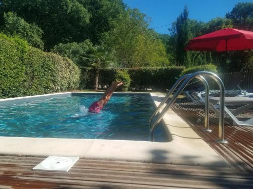 une personne est dans l'eau dans une piscine dans l'établissement Gite Le Piboul, à Espinas