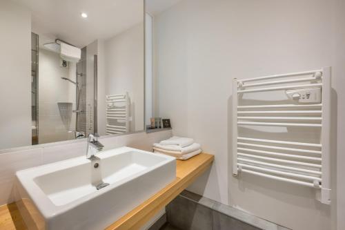a white bathroom with a sink and a shower at H&ocirc;tel Newport in Villefranche-sur-Sa&ocirc;ne