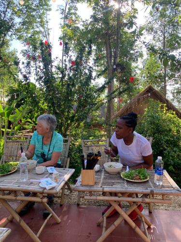 two women sitting at a picnic table eating food at Khu Du Lịch Sinh Thái, Nghỉ dưỡng Homestay Hoàng Ánh - Kon Xom Luh in Kon Tum
