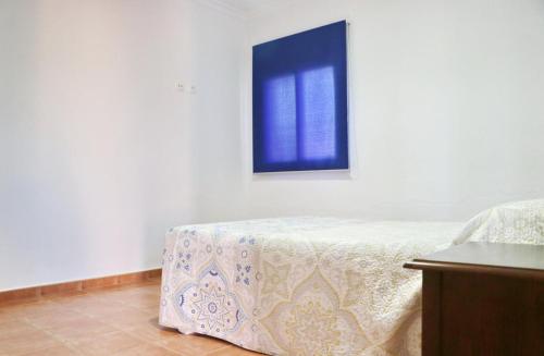 a bedroom with a bed and a blue picture on the wall at Chalet Peñuelas in Conil de la Frontera