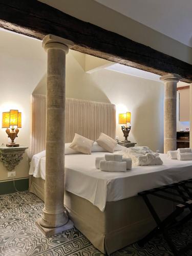 ein großes weißes Bett in einem Zimmer mit zwei Lampen in der Unterkunft Casa Modica - Luxury rooms in Noto