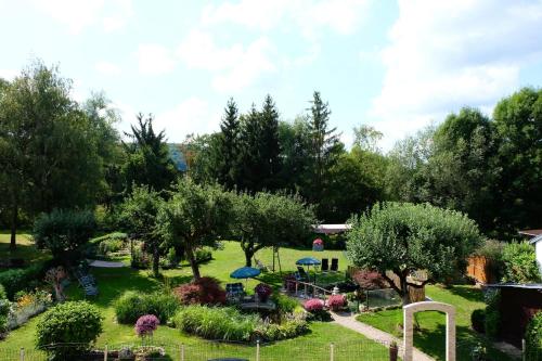 un jardín con árboles, sillas y sombrillas en Gästehaus Biedermann, en Kinding