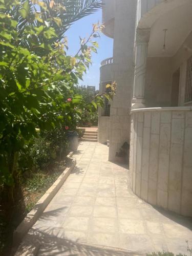 a walkway outside of a building with a tree at Ajloun Rest House in ‘Ayn Jannā