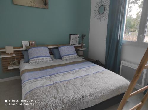 une chambre avec un lit aux murs bleus et une fenêtre dans l'établissement Appartement La Savinière, à La Tranche-sur-Mer