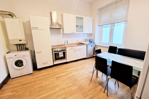 eine Küche mit weißen Schränken sowie einem Tisch und Stühlen in der Unterkunft Central located Apartments in Bergisch Gladbach