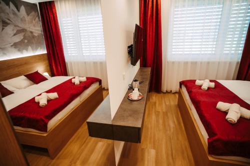 a bedroom with two beds with red sheets and a table at Pension JASOPA in Pardubice
