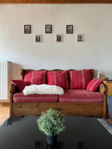 un sofá rojo con almohadas rojas en la sala de estar. en Logement avec vue panoramique à 10min des pistes, en Sauto