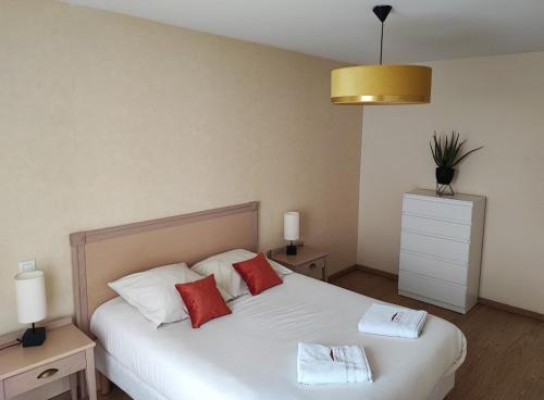 a bedroom with a white bed with red pillows at Domitys Le Jardin des Lys in Alençon