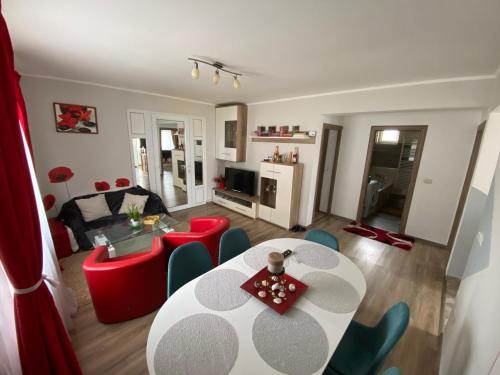 ein Wohnzimmer mit einem Tisch und roten Stühlen in der Unterkunft “Home sweet home” in Sîntandrei